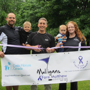 Gillian et sa famille tenant une pancarte sur un terrain de golf pour leur tournoi de golf Mulligans Fore Matthew.